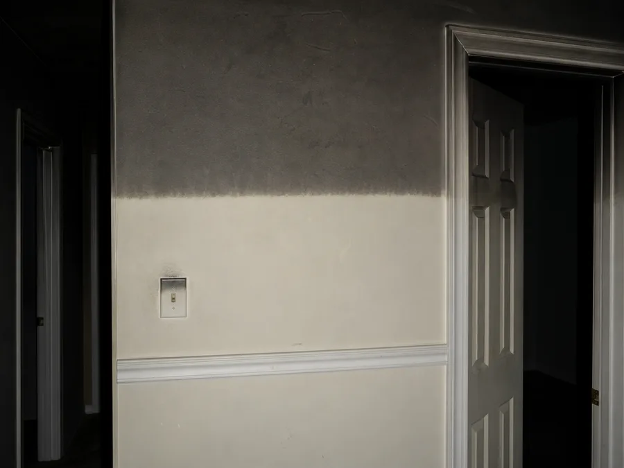 A hallway wall with grey residue across its upper third and clean paint below
